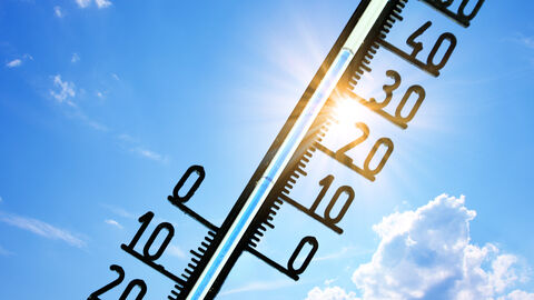 Thermometer vor blauem Himmel und strahlender Sonne. Es zeigt 35 Grad an.