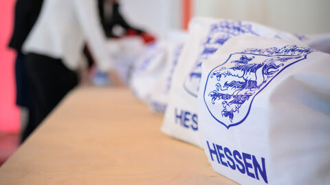 Auf einem Tisch liegen weiße Taschen - auf ihnen ist in blau das neue Logo gedruckt.