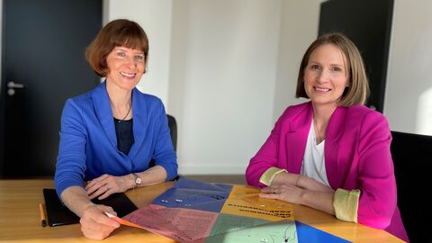 Ministerin Hofmann (links) sitzt gemeinsam mit Miriam Zeleke an einem Tisch. Vor ihnen sind Unterlagen ausgebreitet.