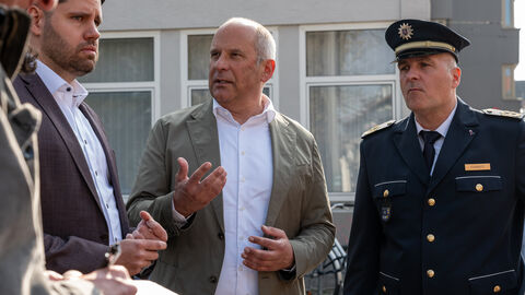 Eine Gruppe von vier Männern steht zusammen und unterhält sich. Einer von ihnen ist ein Polizeibeamter.