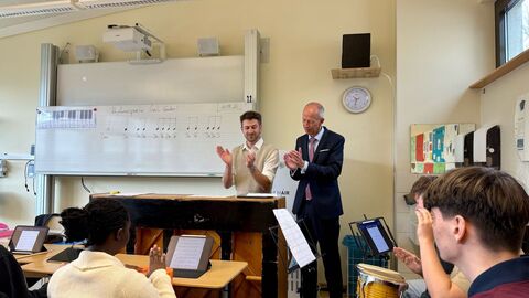 Bildungminister Schwarz steht in einer Schulklasse vorne neben einem Lehrer.